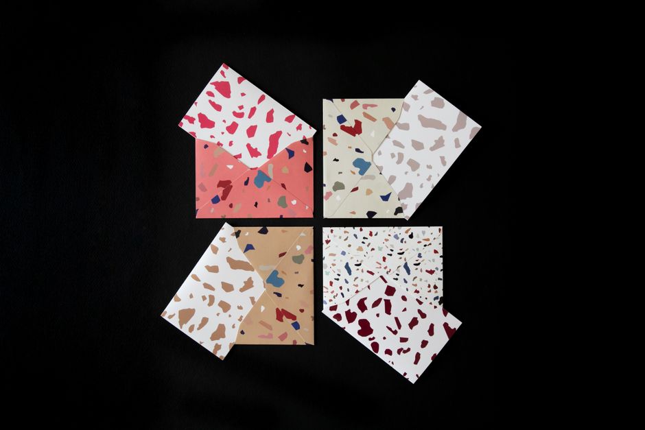 Stylish terrazzo patterned envelopes in vibrant colors on a black background.